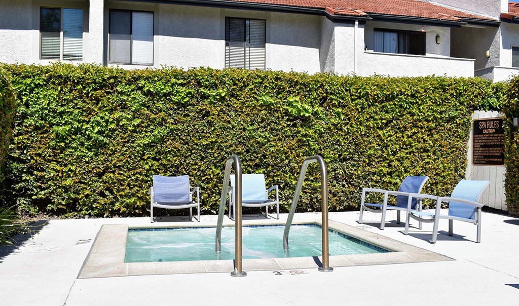 View of spa, lounge chairs, and shrubbery