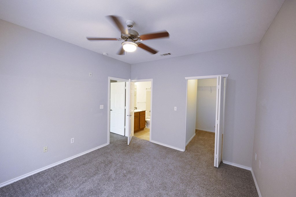 View from bedroom into walk in closet and ensuit bathroom, with carpet flooring