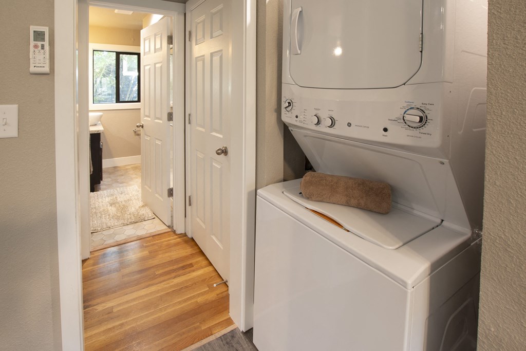 View of hall area with stackable washer and dryer and view into bathroom