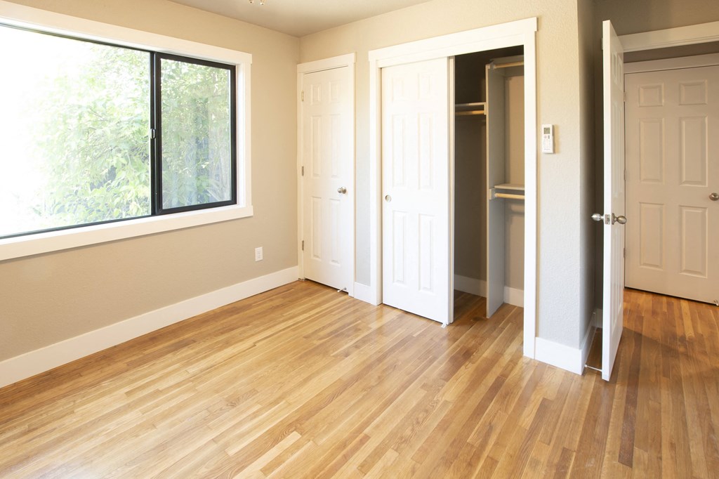 View of bedroom with wood look flooring, closet, and well lit window