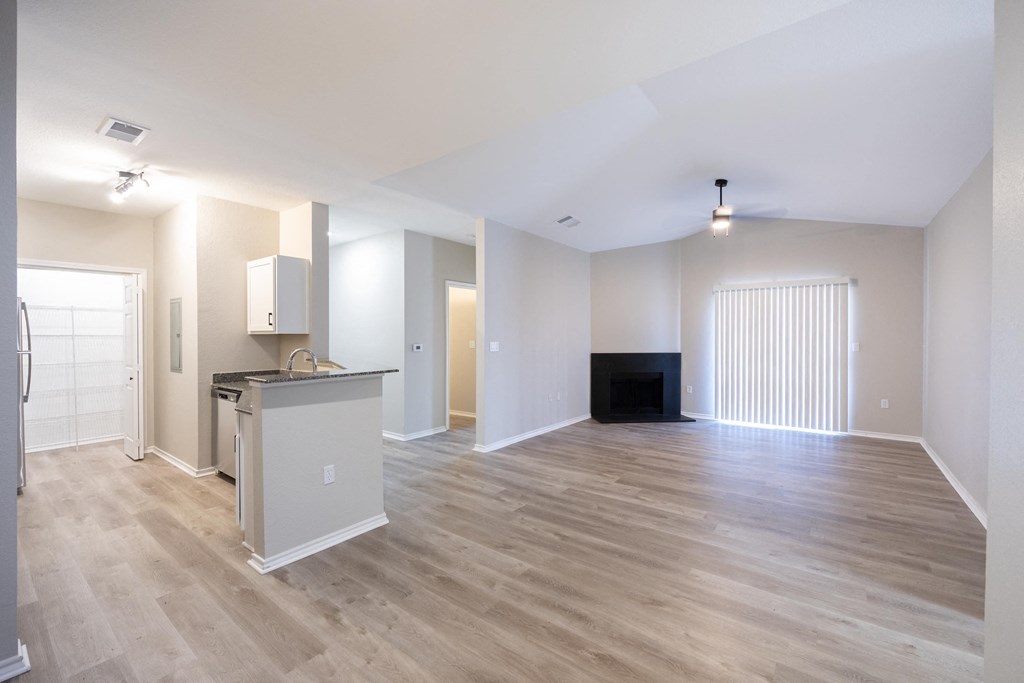an empty living room and kitchen with a wood floor