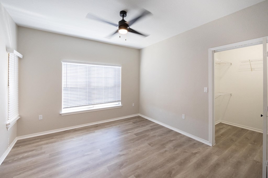 an empty bedroom with a ceiling fan and a window