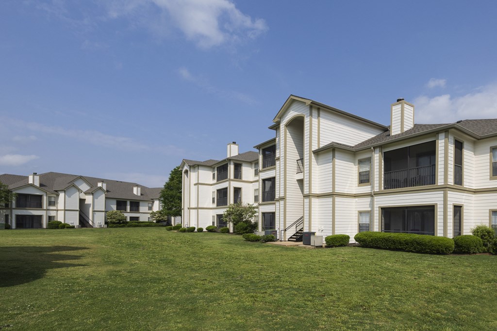 a group of white apartment buildings on a green lawn