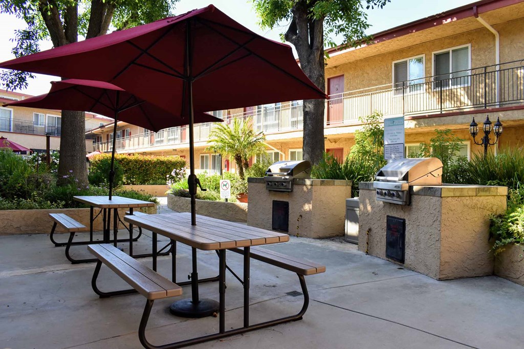 courtyard with grilling station and picnic tables with umbrellas providing shade