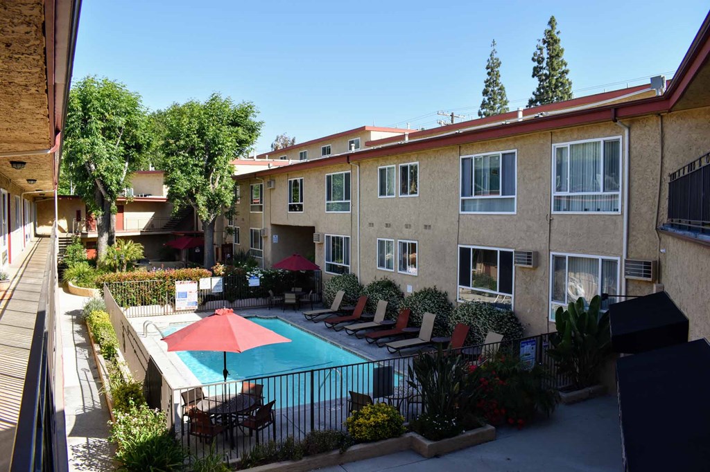 elevated view of gated community pool with lounge chairs and seating under umbrellas