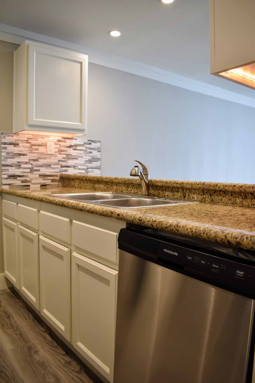 kitchen with stone counters, stainless appliances, in laid sink, tile backsplash, white cabinets, and recessed lighting