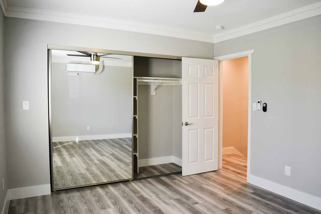 bedroom with wood look flooring, large sliding mirror closet