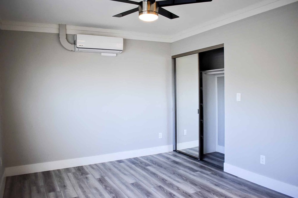 bedroom with sliding mirror closet, wood look flooring, and ceiling fan