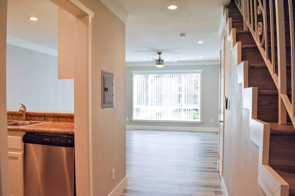 view into living room with wood look flooring, well lit window, and ceiling fan