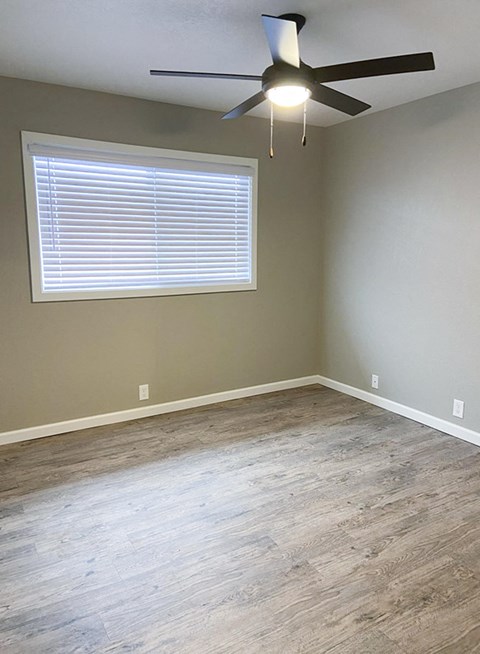 an empty living room with wood floors and a ceiling fan