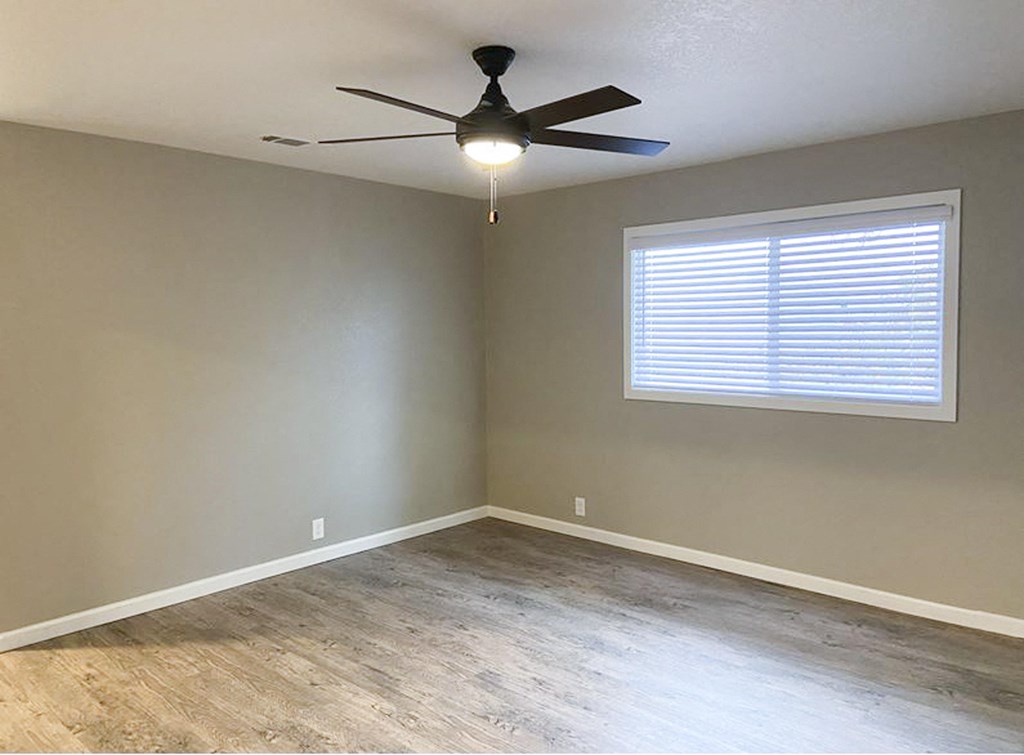 living room with wood look flooring, ceiling fan, and well lit window