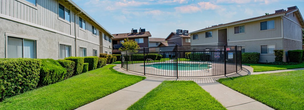 Gated community pool with green landscaping at Sutter Apartments