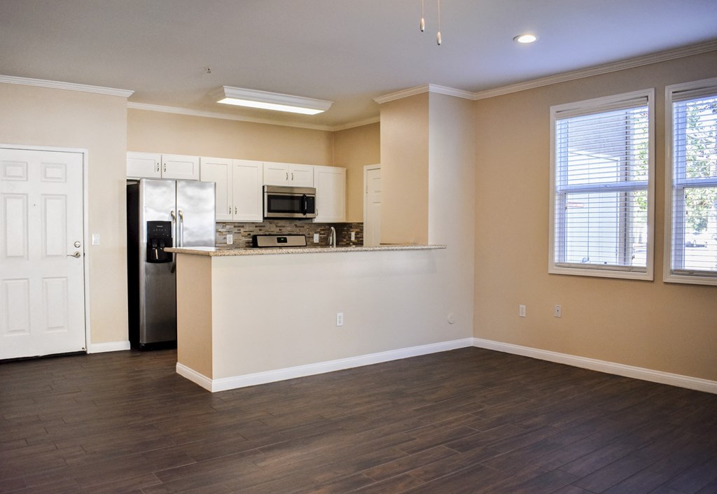 view from living room to kitchen with wood look flooring and well lit windows