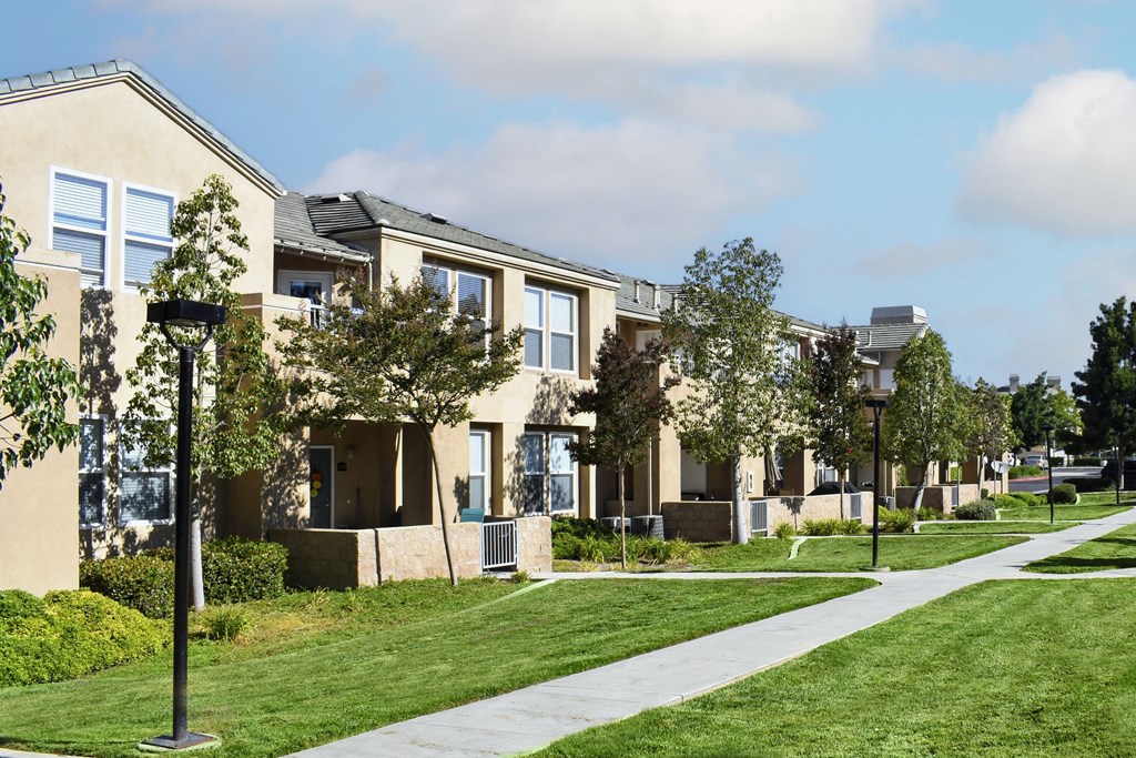 a row of apartments on a sidewalk with grass and trees