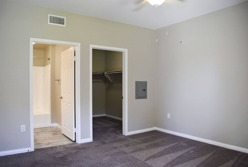 Bedroom looking into walk in closet and en suit bathroom. Has carpet flooring in bedroom and tile flooring in bathroom