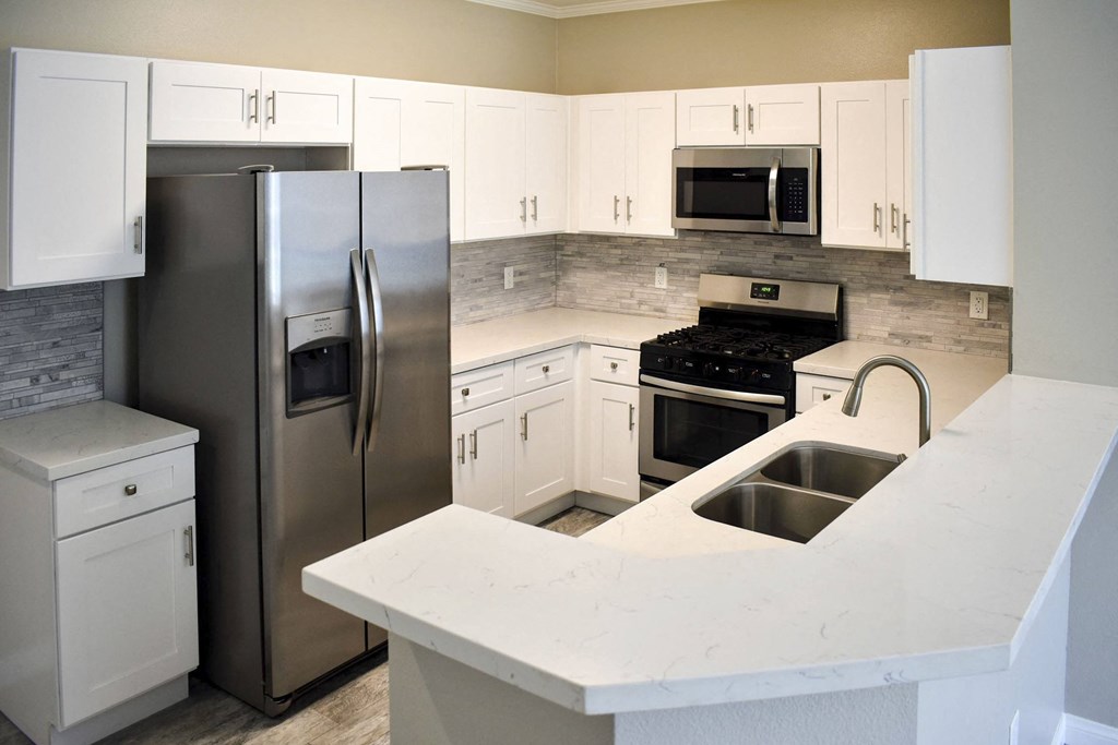 kitchen with light countertops, tile backsplash, stainless appliances, and white cabinets