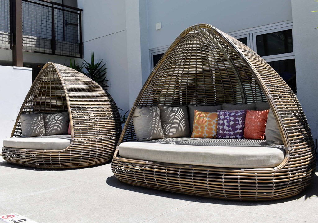 two rattan chairs with cushions in front of a building