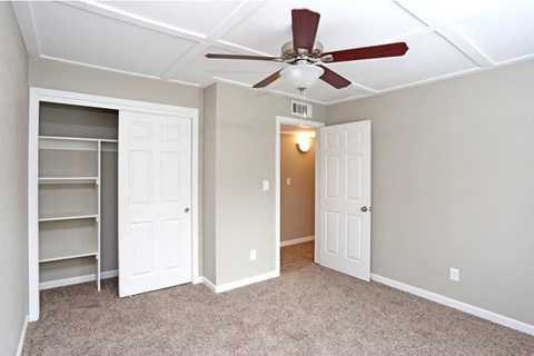 a bedroom with a ceiling fan and a closet