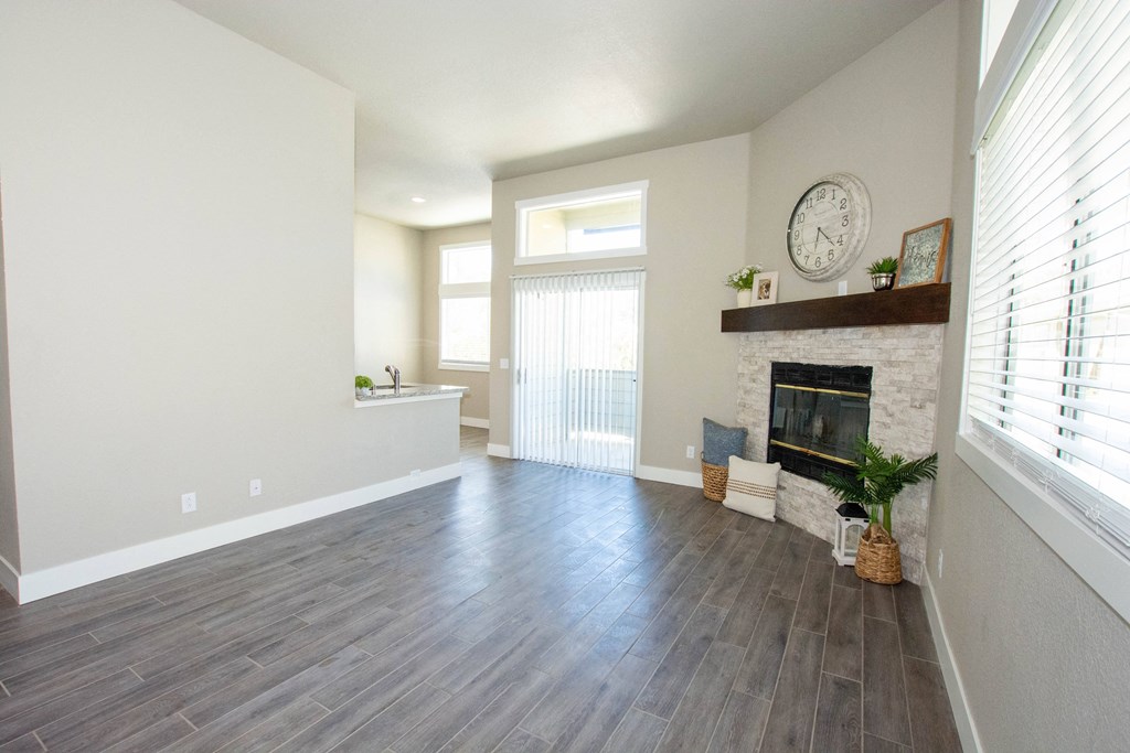 an empty living room with a fireplace and wooden floors