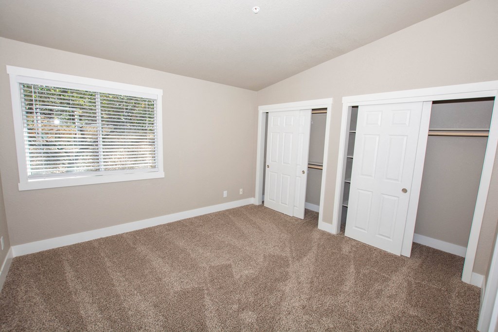 an empty bedroom with a window and a closet