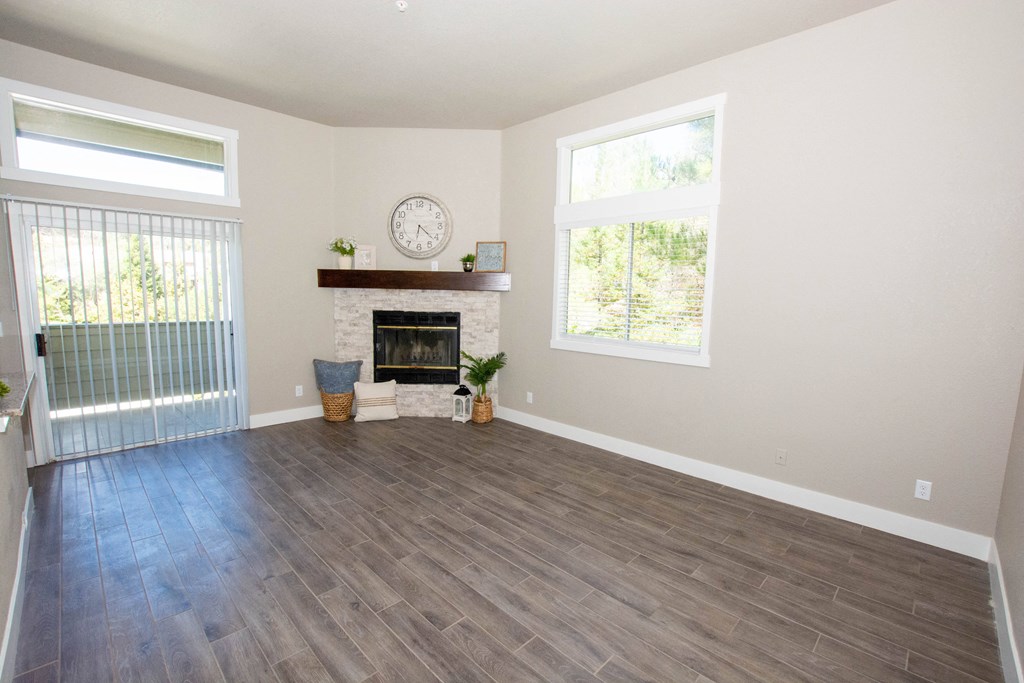 an empty living room with a fireplace and a clock on the wall