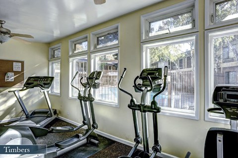 a workout room with treadmills and windows