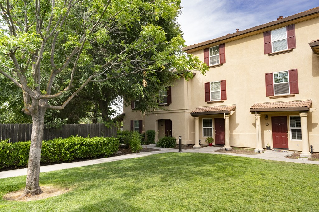 building at Tuscana with a lawn and trees in front of it