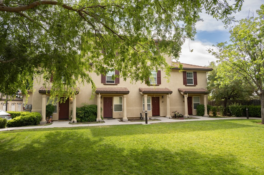 building at Tuscana with a lawn and trees in front of it