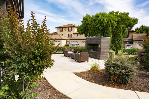 a concrete walkway leads to a stone fireplace and seating area at Tuscana
