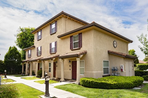 building at Tuscana with a lawn and trees in front of it
