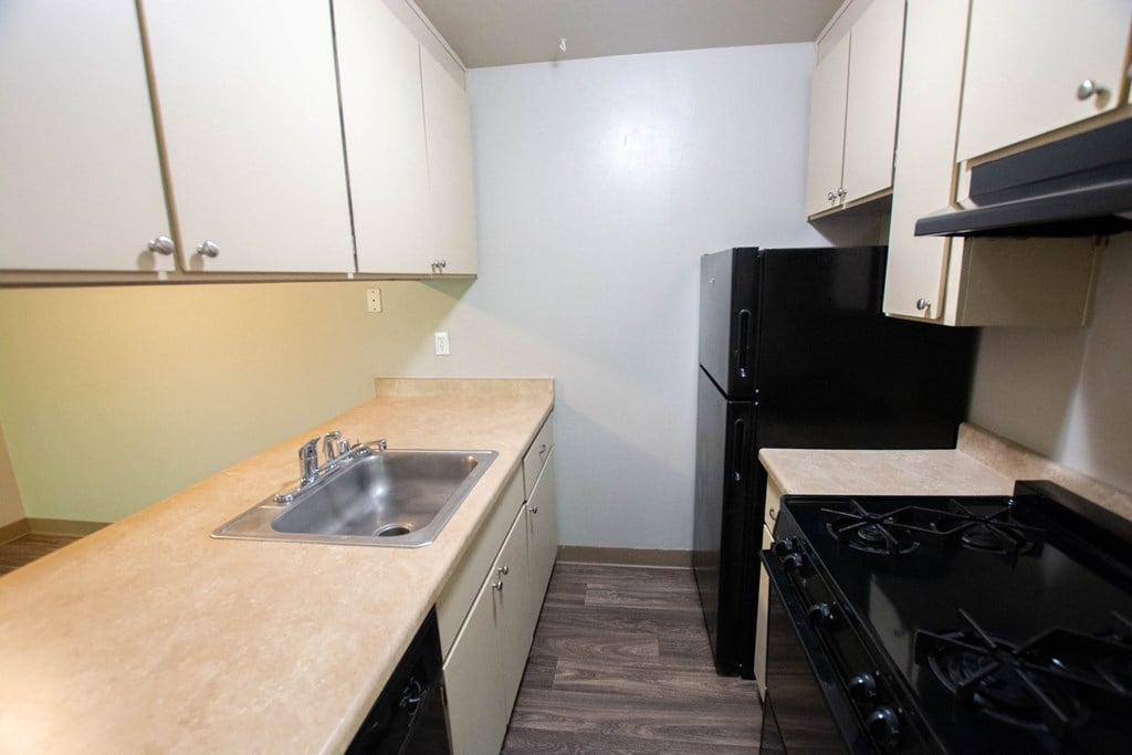a kitchen with white cabinets and black appliances and a sink