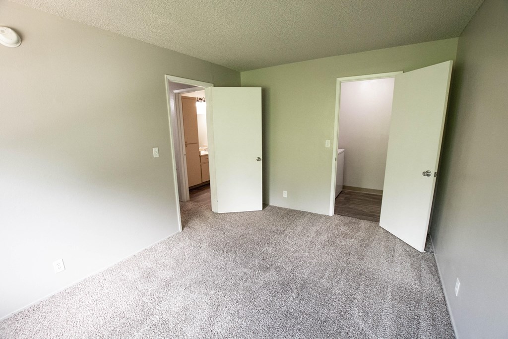 an empty room with three doors and a carpeted floor