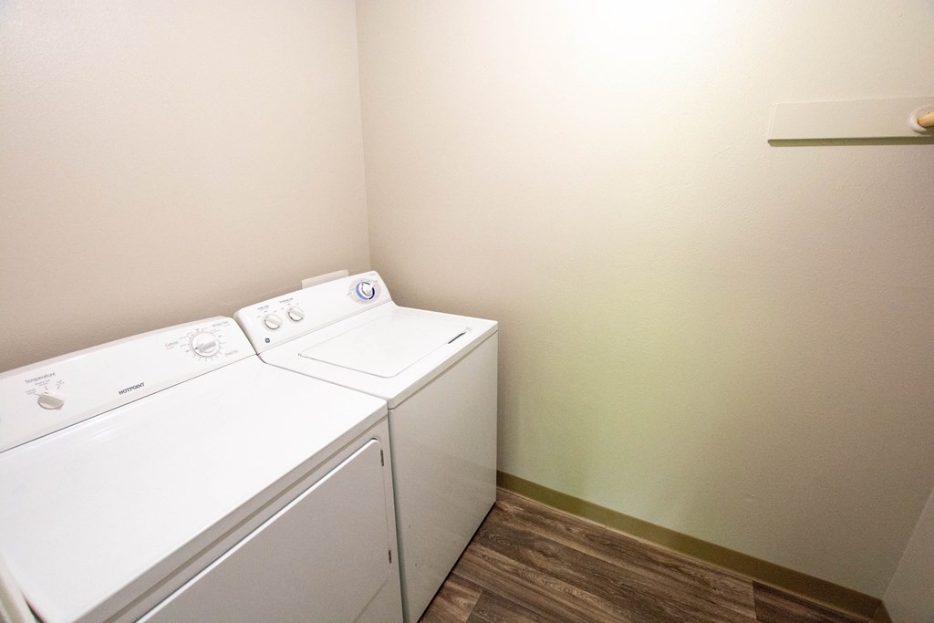 a washer and dryer in a room with a wood floor and white walls