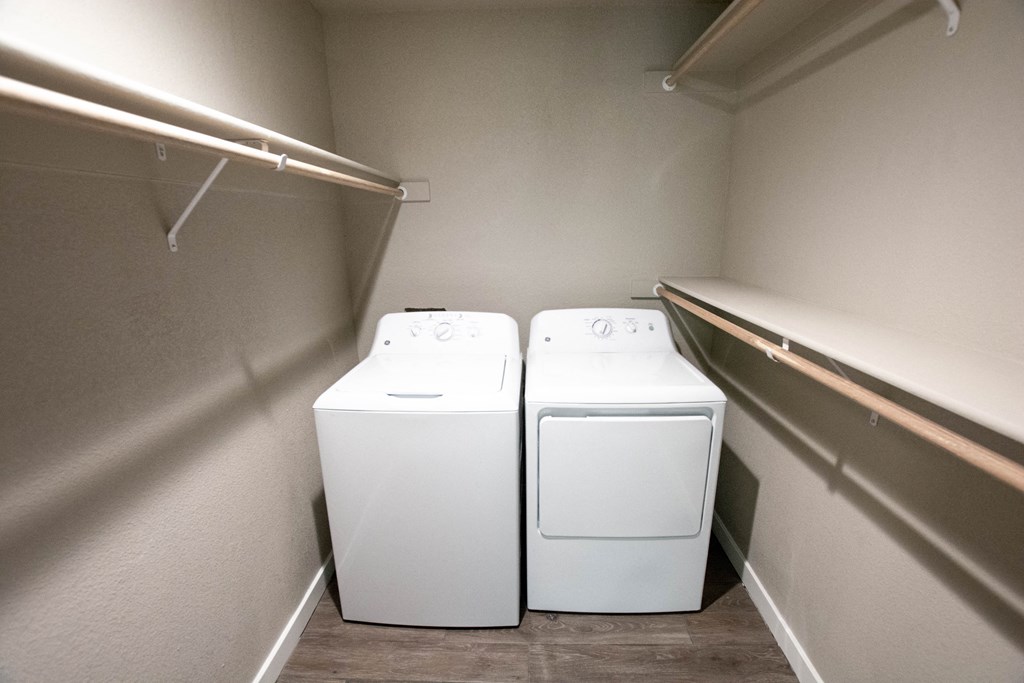 two washers and dryers in a laundry room with a shelf