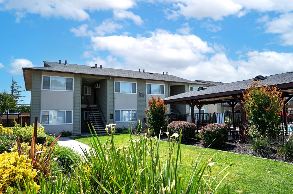 View of the well landscaped and blooming courtyard, exterior of buildings, and gated community pool area at Villas at Fair Oaks