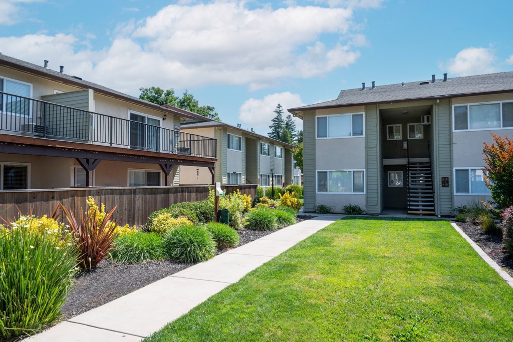 View of courtyard with exterior building in back ground and lush landscaping around private patio/balcony