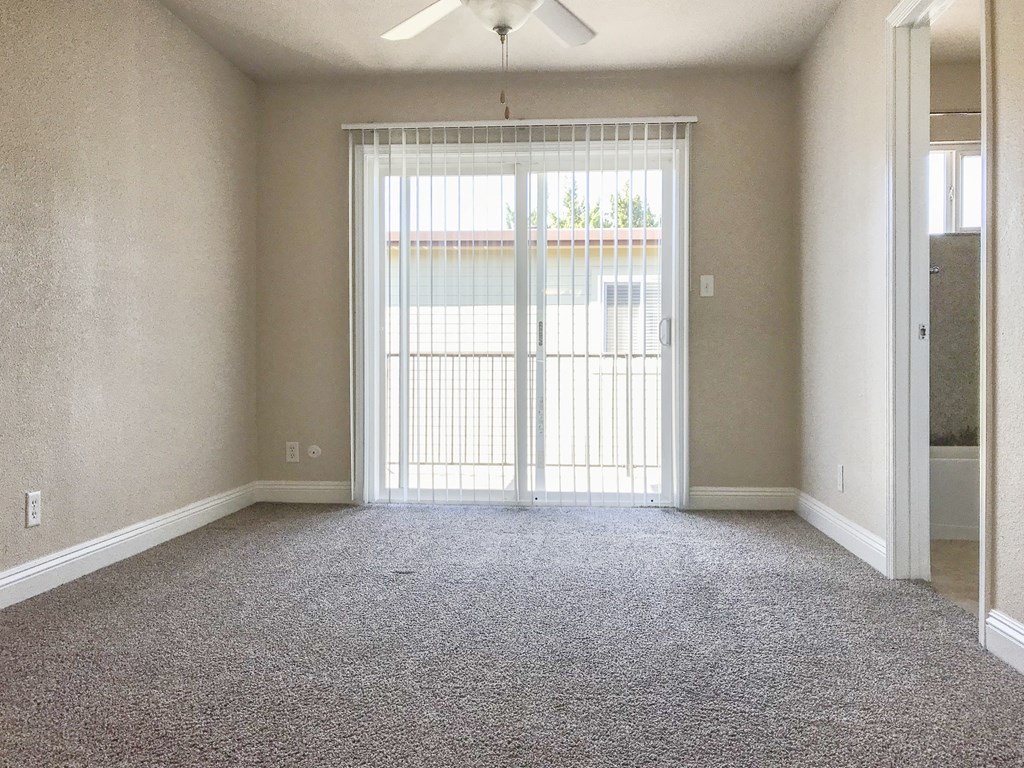 View of bedroom with private patio/balcony access and ceiling fan with carpet flooring