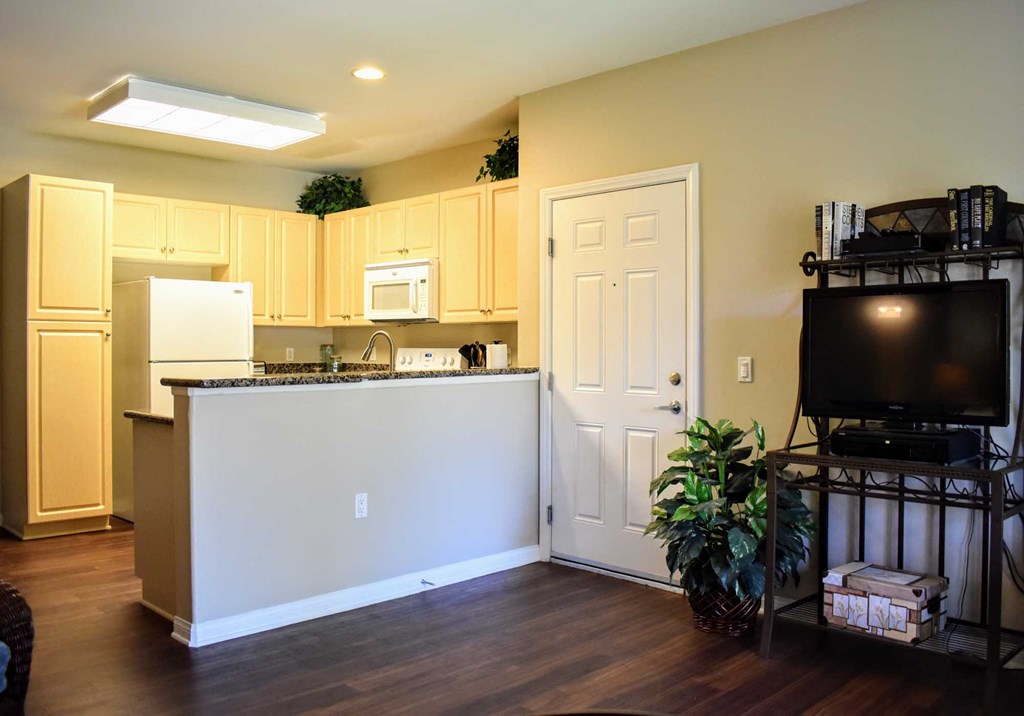 A living room looking into a kitchen withh white appliances