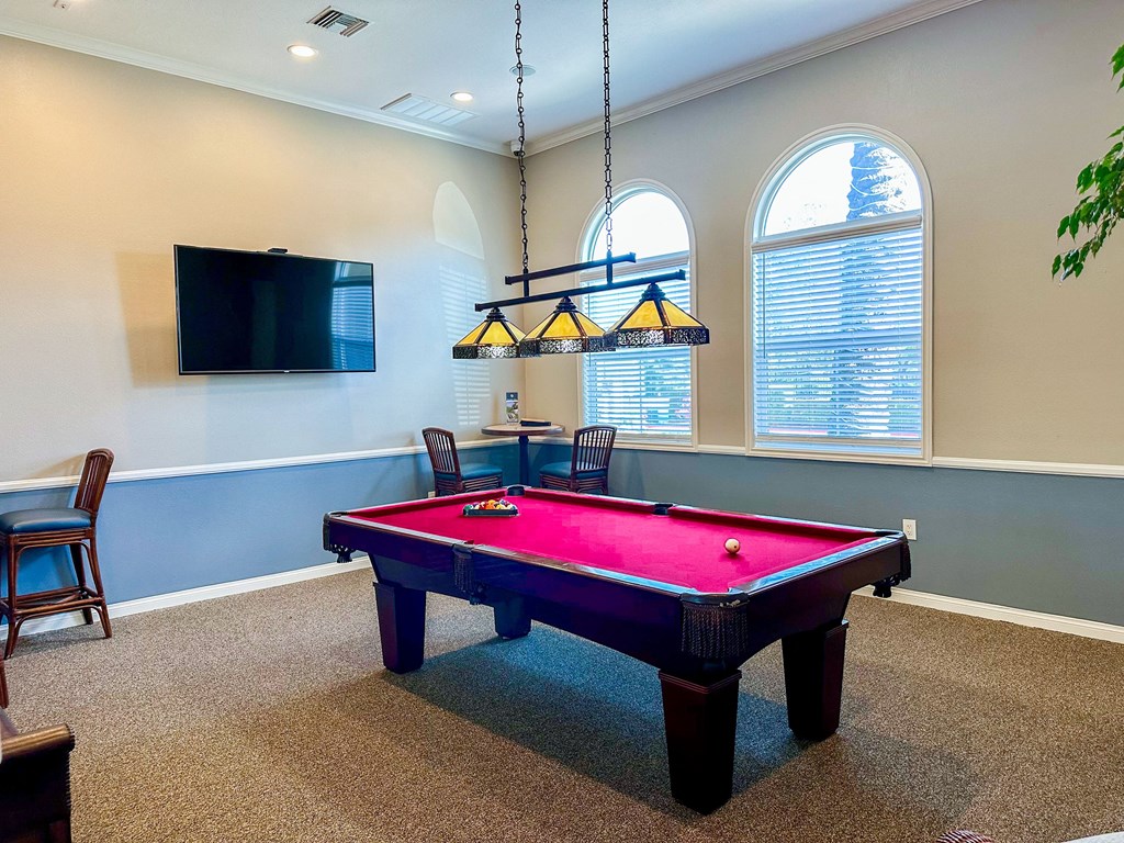 a game room with a pink pool table and a tv