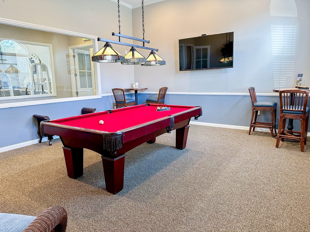 a red pool table in a game room with chairs and a tv