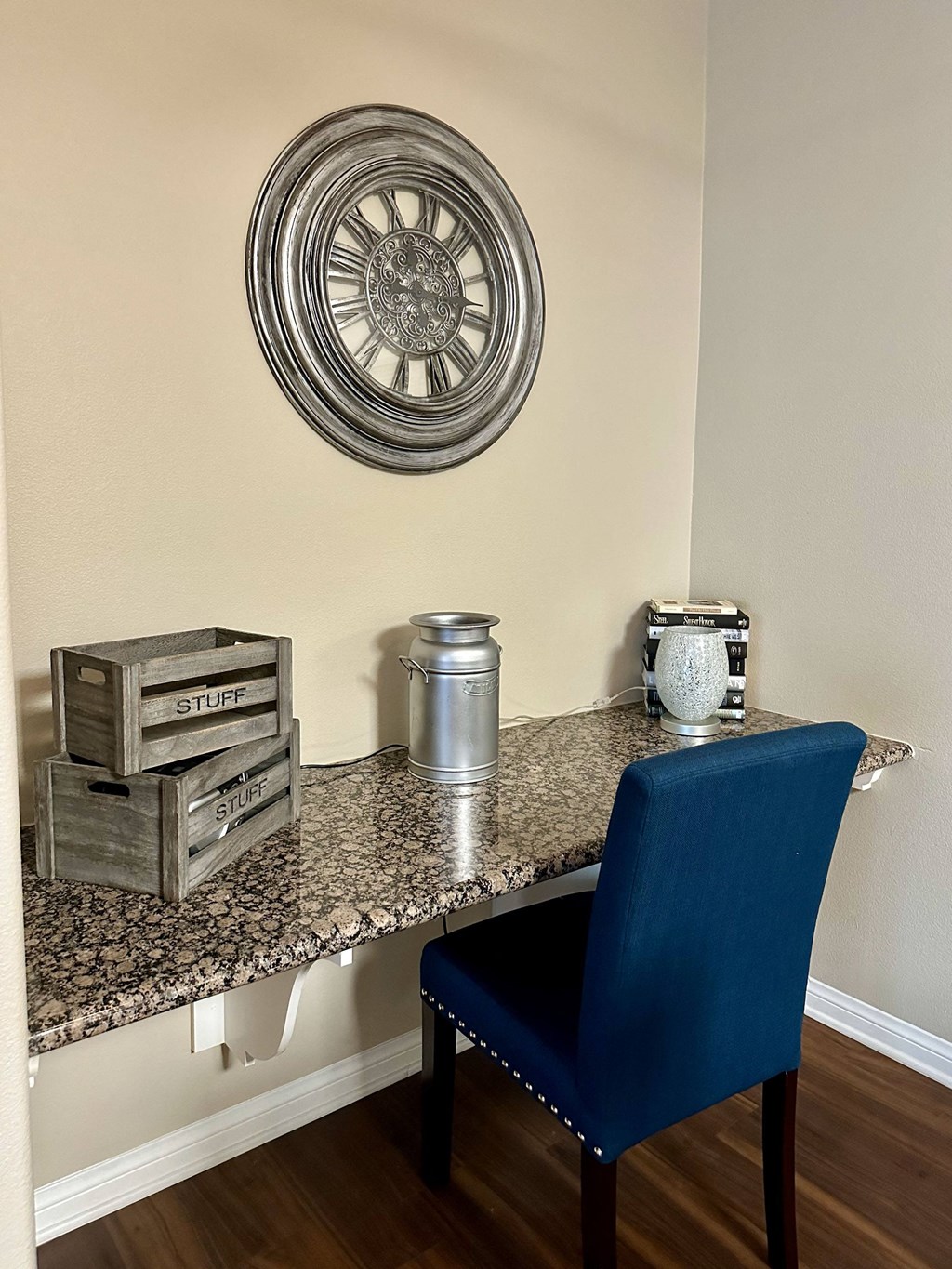 a desk with a blue chair and a clock on the wall