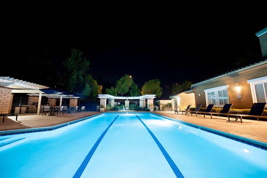 a swimming pool at night next to a clubhouse