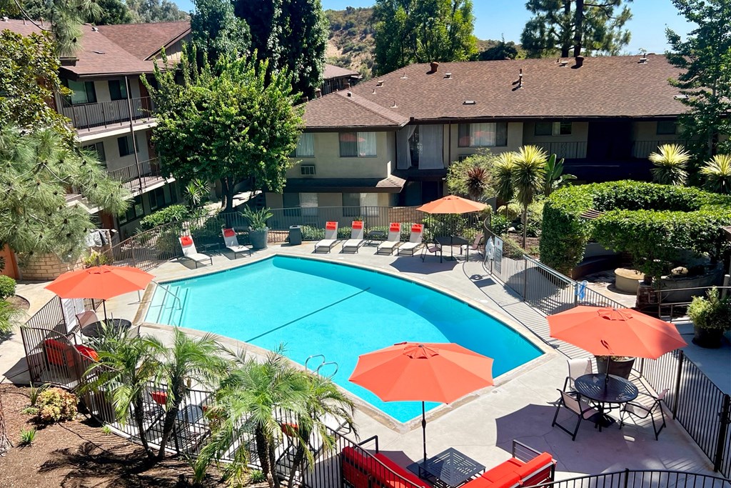 a swimming pool with umbrellas in front of a house
