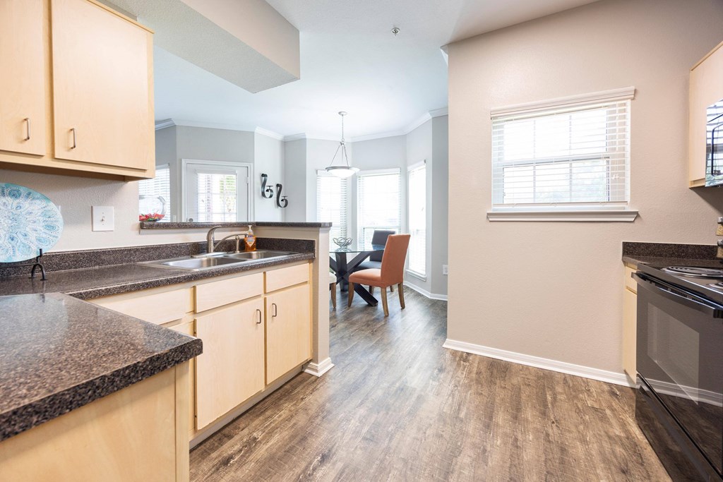 the view of a kitchen and living room with wood floors and granite counter tops