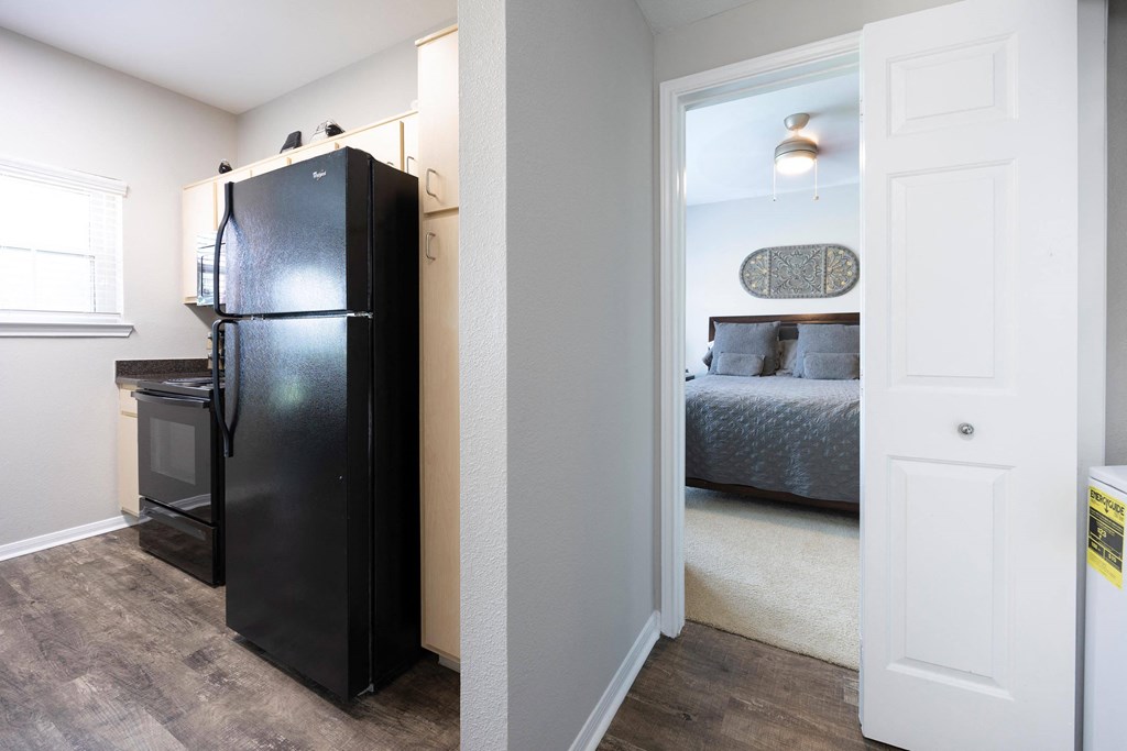 a bedroom with a black refrigerator and a door to a closet