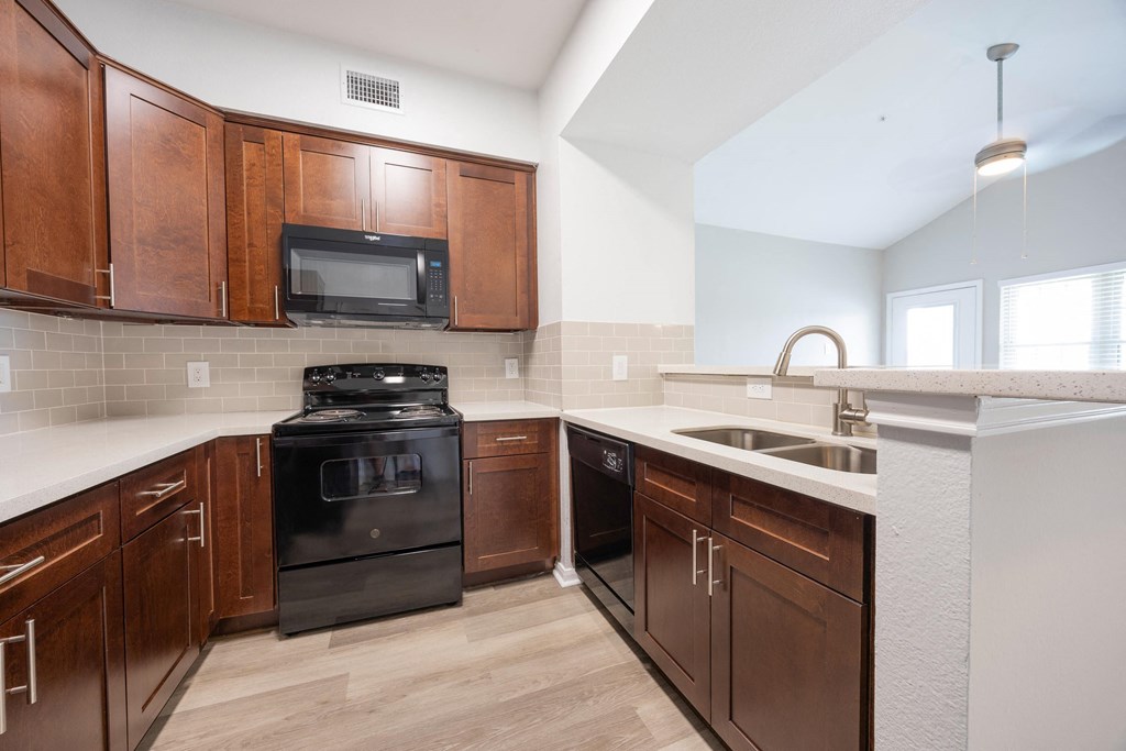 an empty kitchen with wooden cabinets and black appliances