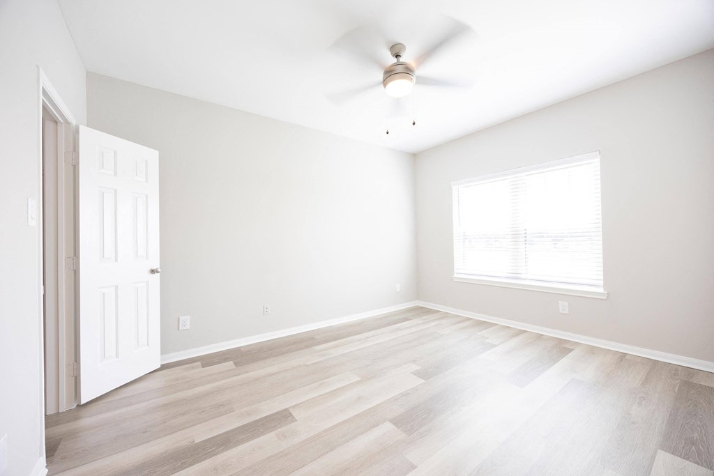 an empty living room with white walls and a ceiling fan