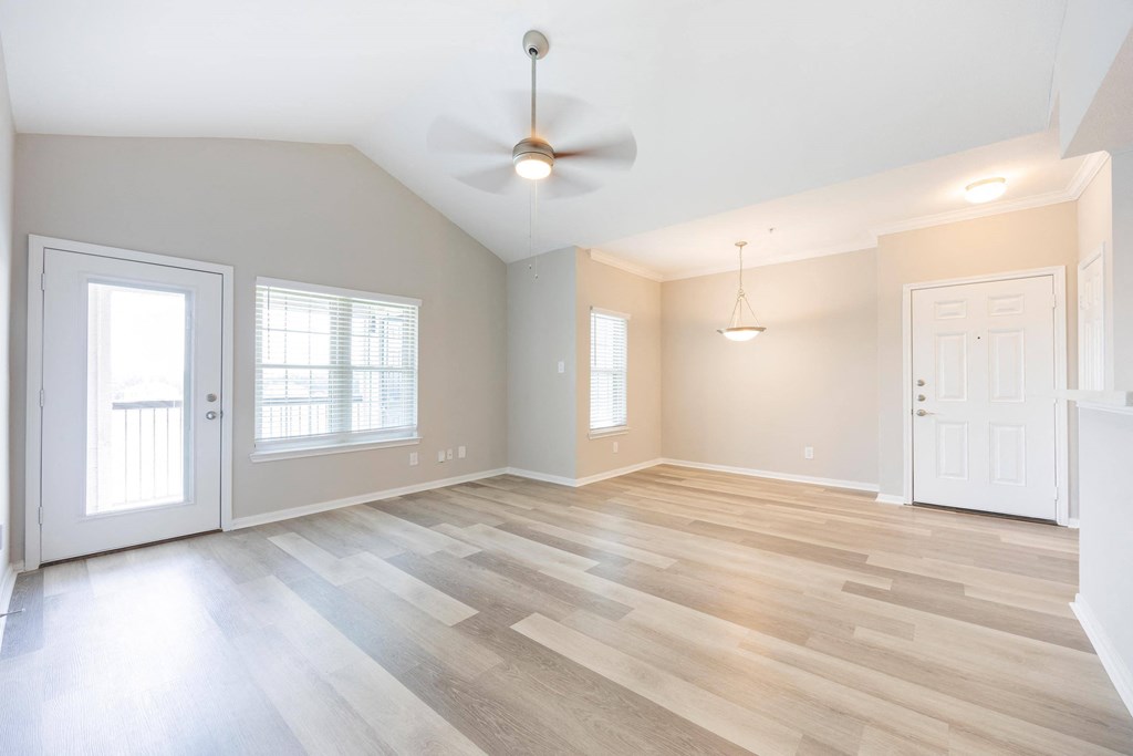 an empty living room with wood floors and a ceiling fan