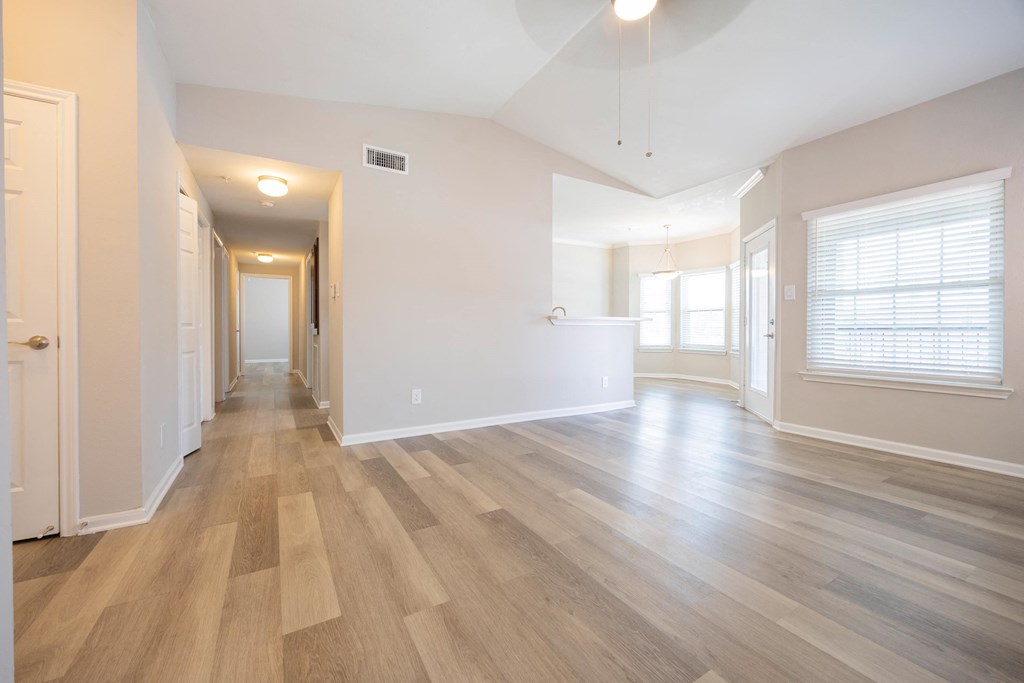 the living room and dining room of an empty house with wood flooring