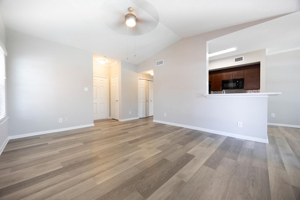 the living room and kitchen of an empty apartment with wood flooring